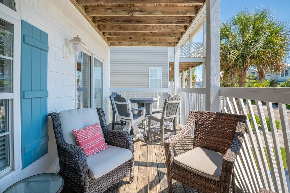 This image features a comfortable outdoor seating area with decorative cushions and an outdoor dining table, set against a backdrop of palm trees. The scene evokes a peaceful, inviting atmosphere, perfect for relaxing or socializing while enjoying the surrounding natural beauty.