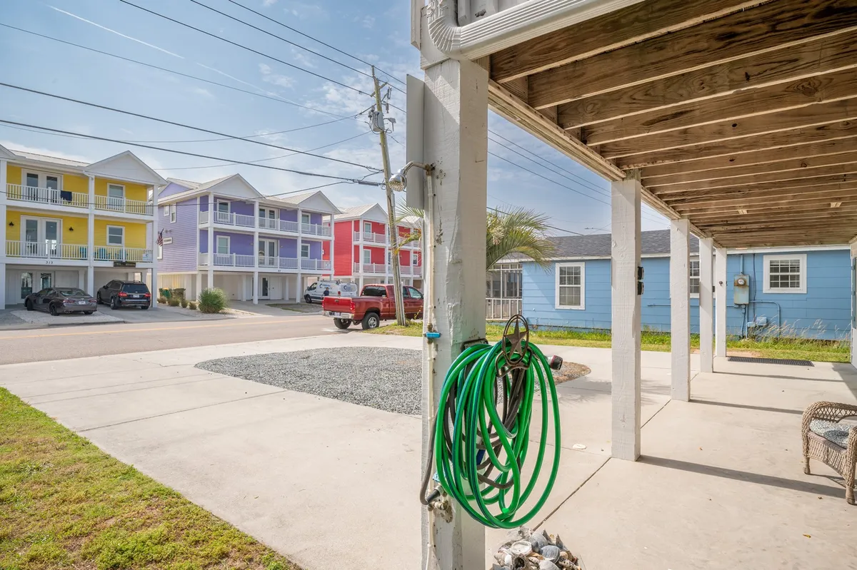 A playful exterior shot with colorful buildings, a green garden hose, a gravel area, and hints of outdoor activity. The space suggests casual gatherings and fun moments enjoyed in the fresh air, resonating with the boardwalk's lively spirit.
